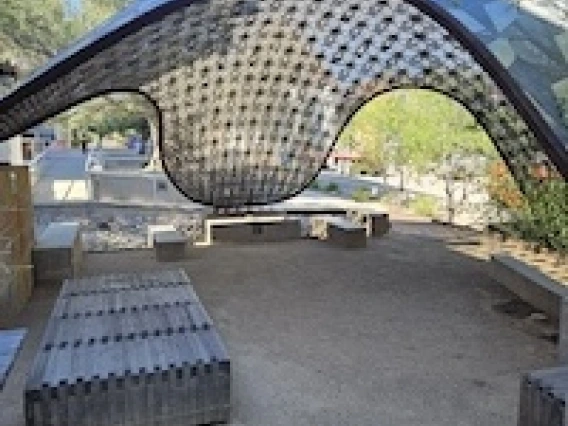 Shaded benches underneath a curved gridshell pavilion