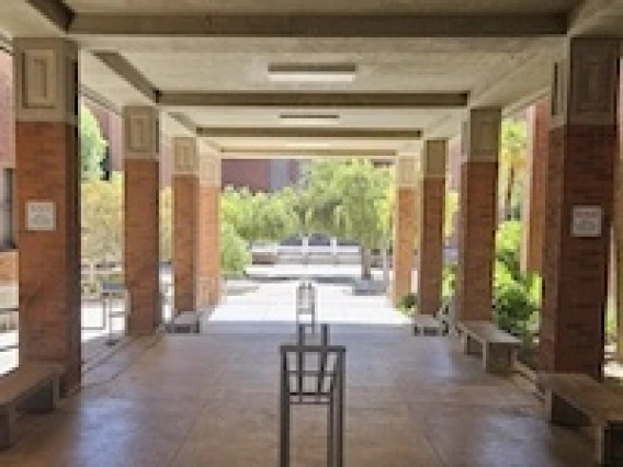 A breezeway bordered by red brick columns leads into a courtyard with trees.
