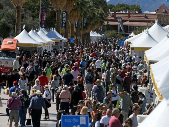 large crowd of people walking near white tents on the University of Arizona Mall