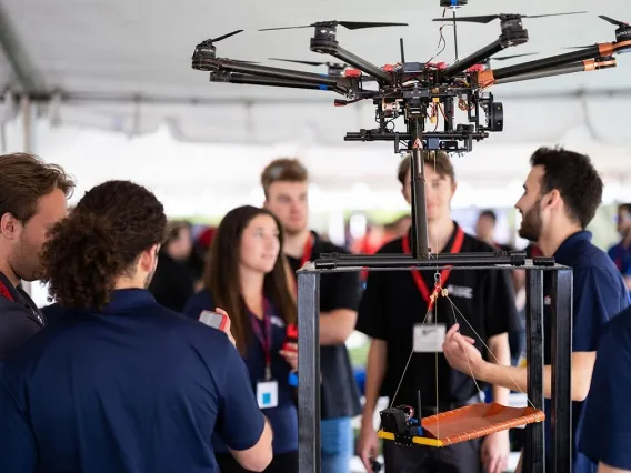 people standing under a tent while demonstrating a robotic system for exploring Mars