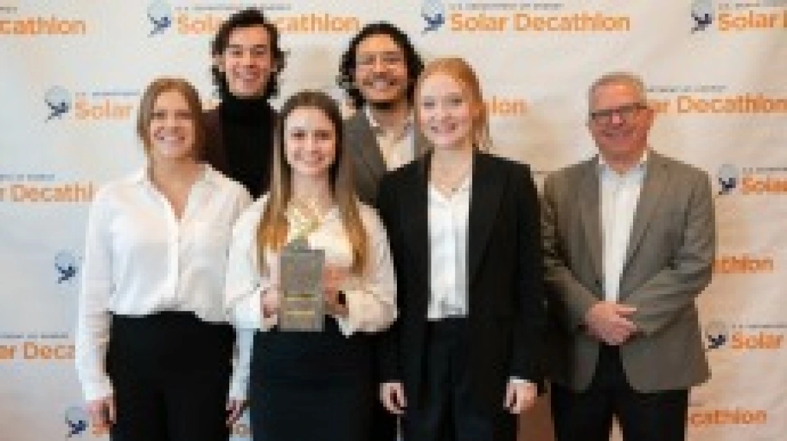 six people standing for a group photo with one holding an award