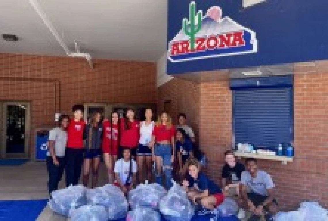 students posing with several bags of donated shoes